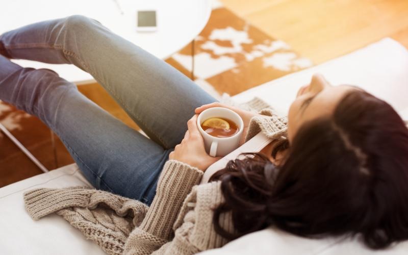 a person lying on a bed with a cup of coffee